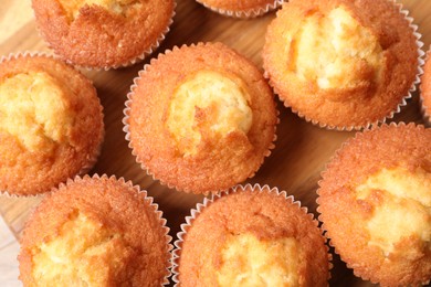 Delicious sweet muffins on wooden board, flat lay