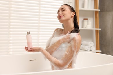 Photo of Woman taking bath with shower gel in bathroom