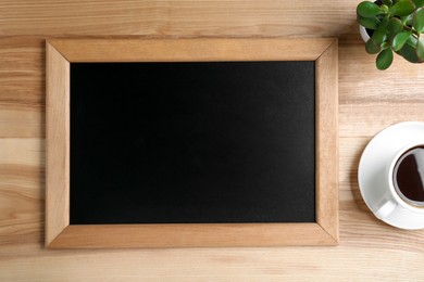 Photo of Clean small chalkboard, coffee and plant on wooden table, flat lay