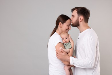 Happy family. Parents with their cute baby on grey background, space for text