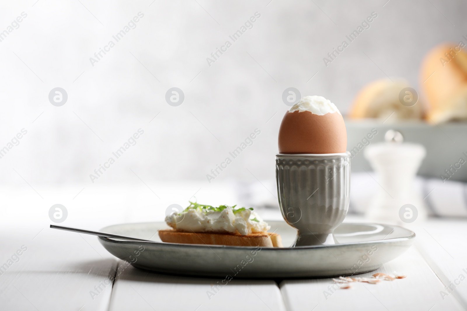 Photo of Fresh soft boiled egg in cup and sandwich on white wooden table. Space for text