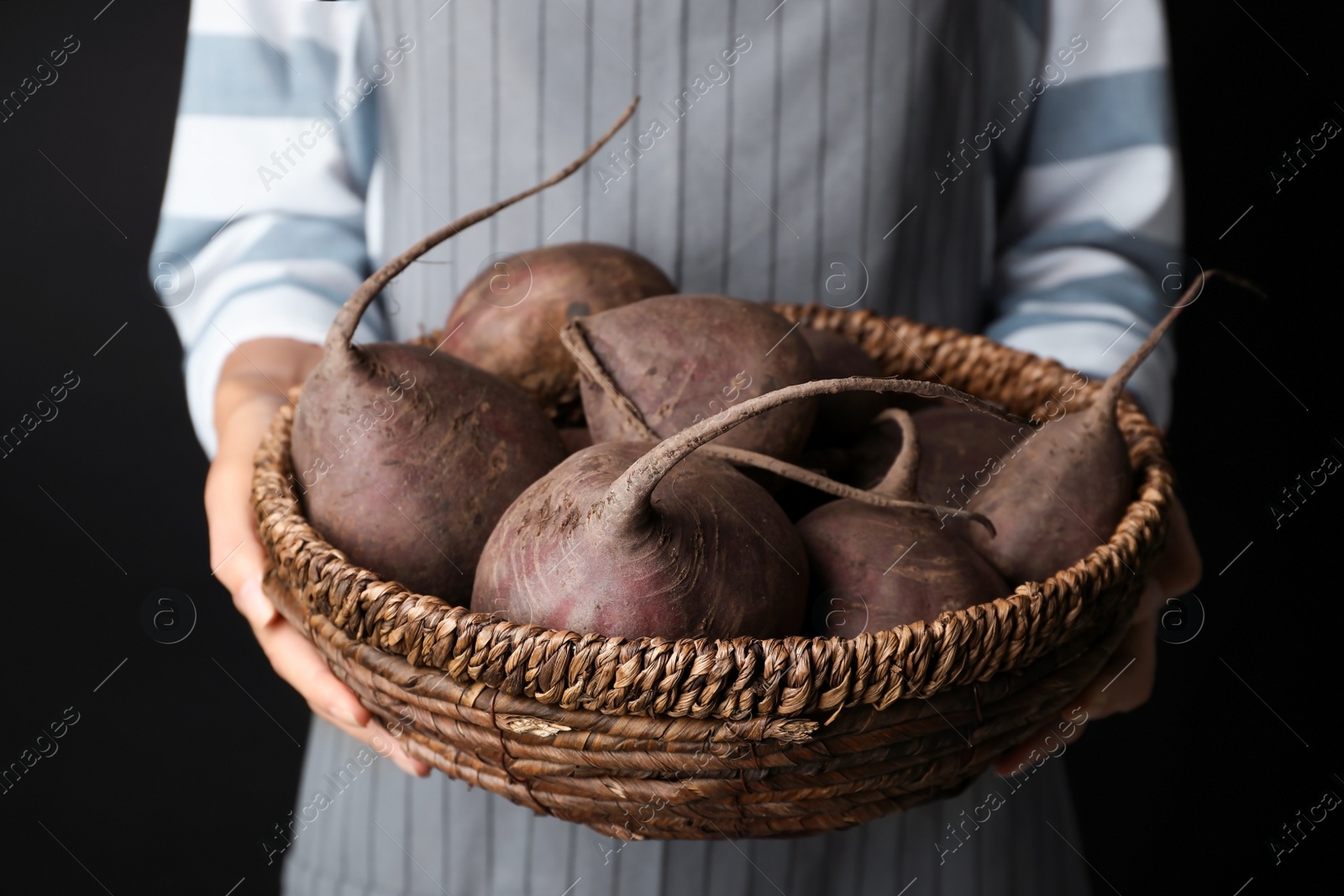 Photo of Woman holding bowl with beets on black background