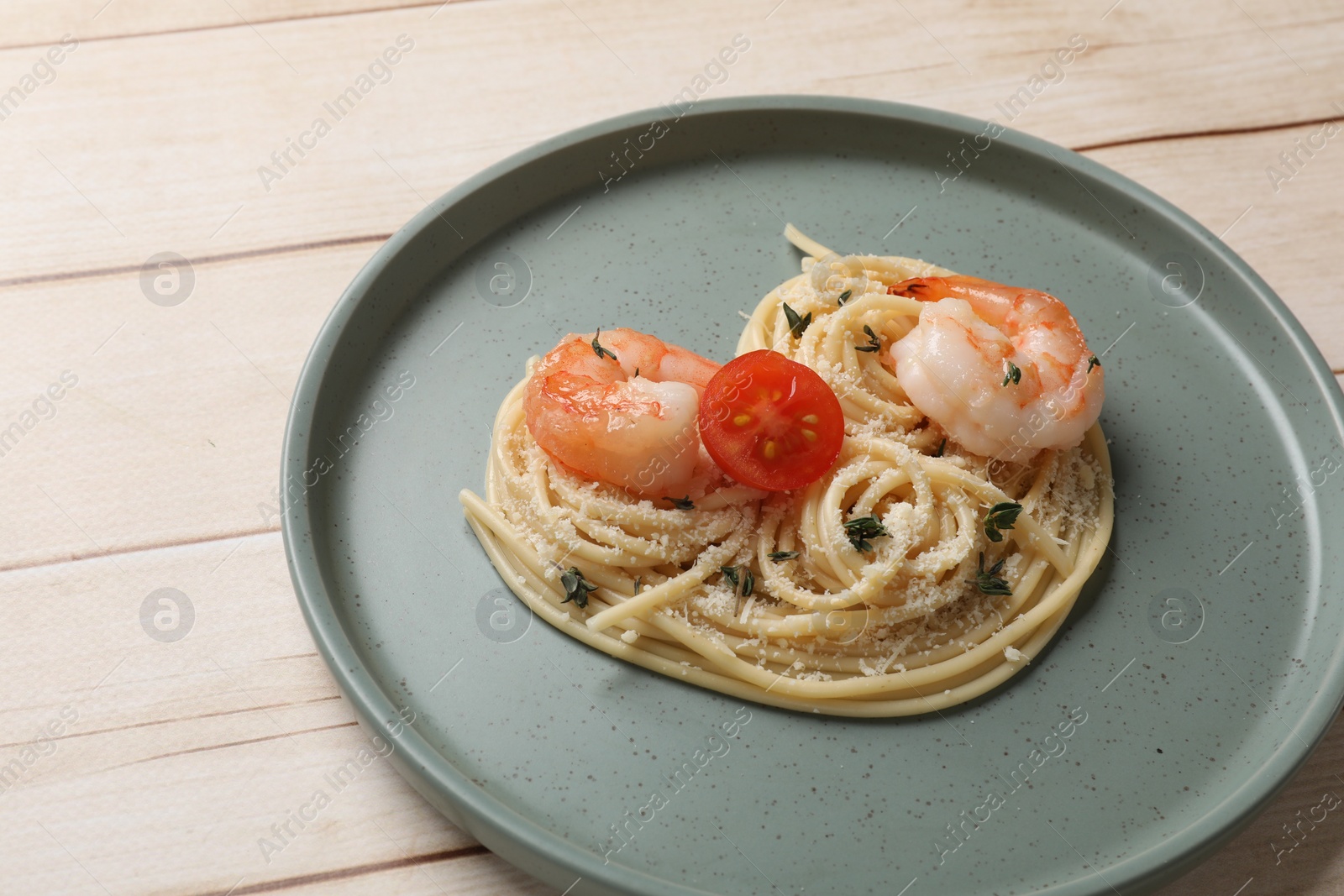 Photo of Heart made of tasty spaghetti, tomato, shrimps and cheese on light wooden table, closeup