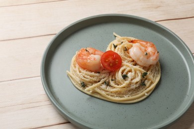 Photo of Heart made of tasty spaghetti, tomato, shrimps and cheese on light wooden table, closeup