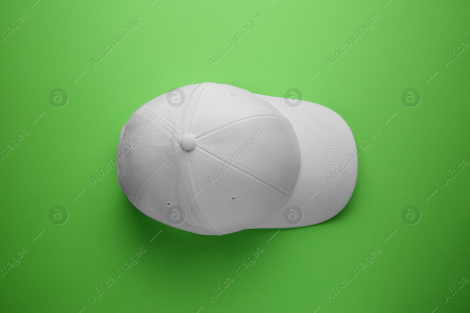 Photo of Stylish white baseball cap on light green background, top view