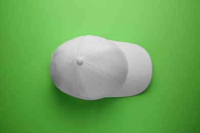 Photo of Stylish white baseball cap on light green background, top view