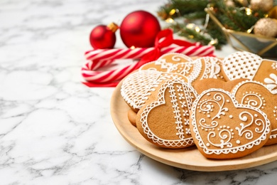 Photo of Tasty heart shaped gingerbread cookies and Christmas decor on white marble table, closeup. Space for text