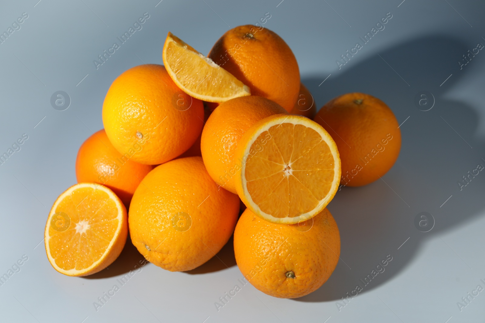 Photo of Many whole and cut oranges on grey background