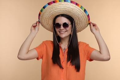 Photo of Young woman in Mexican sombrero hat and sunglasses on beige background