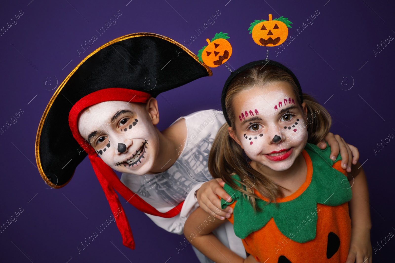 Photo of Cute little kids wearing Halloween costumes on purple background