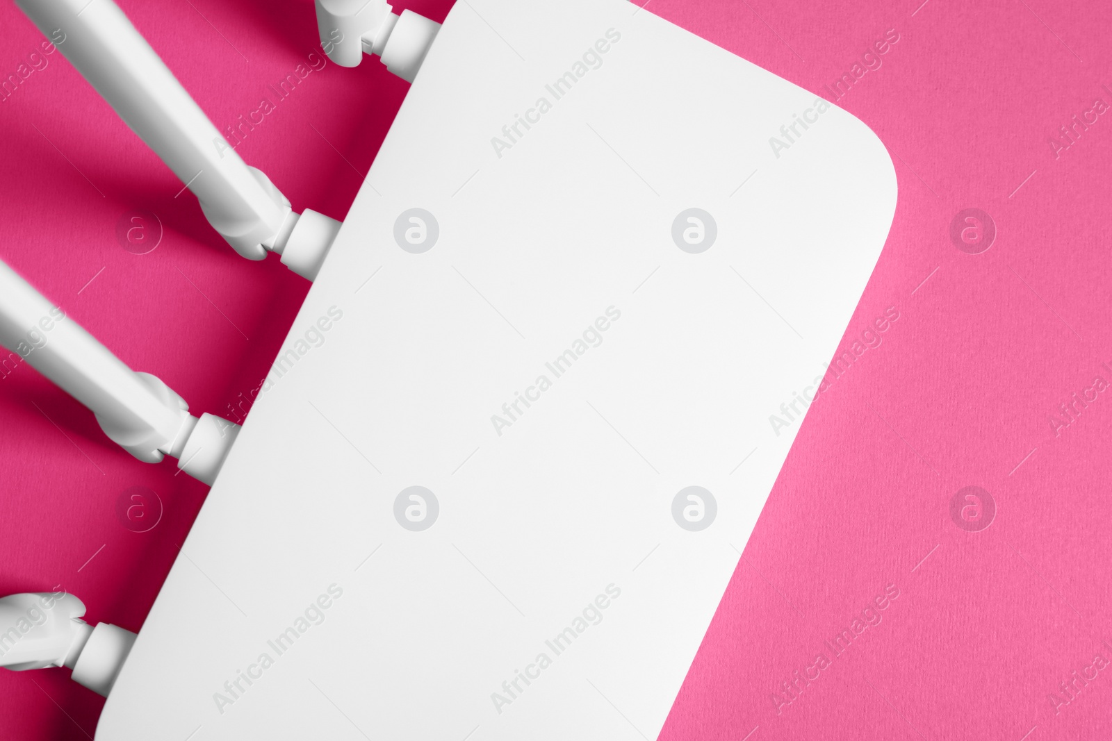 Photo of New white Wi-Fi router on pink background, top view