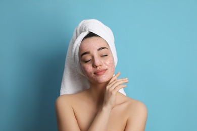 Photo of Woman with pomegranate face mask on light blue background