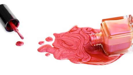 Photo of Overturned bottle of bright nail polish and brush isolated on white