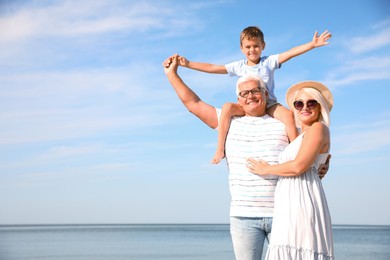 Photo of Cute little boy with grandparents spending time together on sea beach