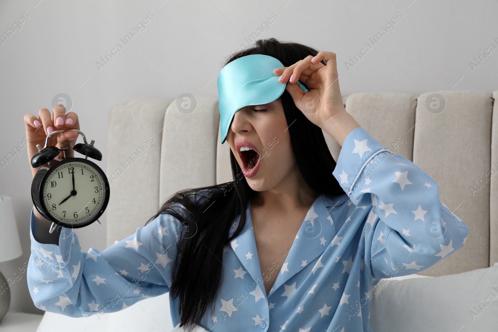 Photo of Emotional overslept woman with alarm clock in bed. Being late concept