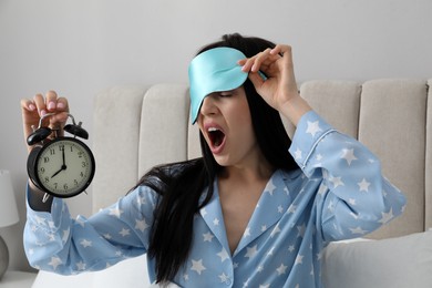 Photo of Emotional overslept woman with alarm clock in bed. Being late concept