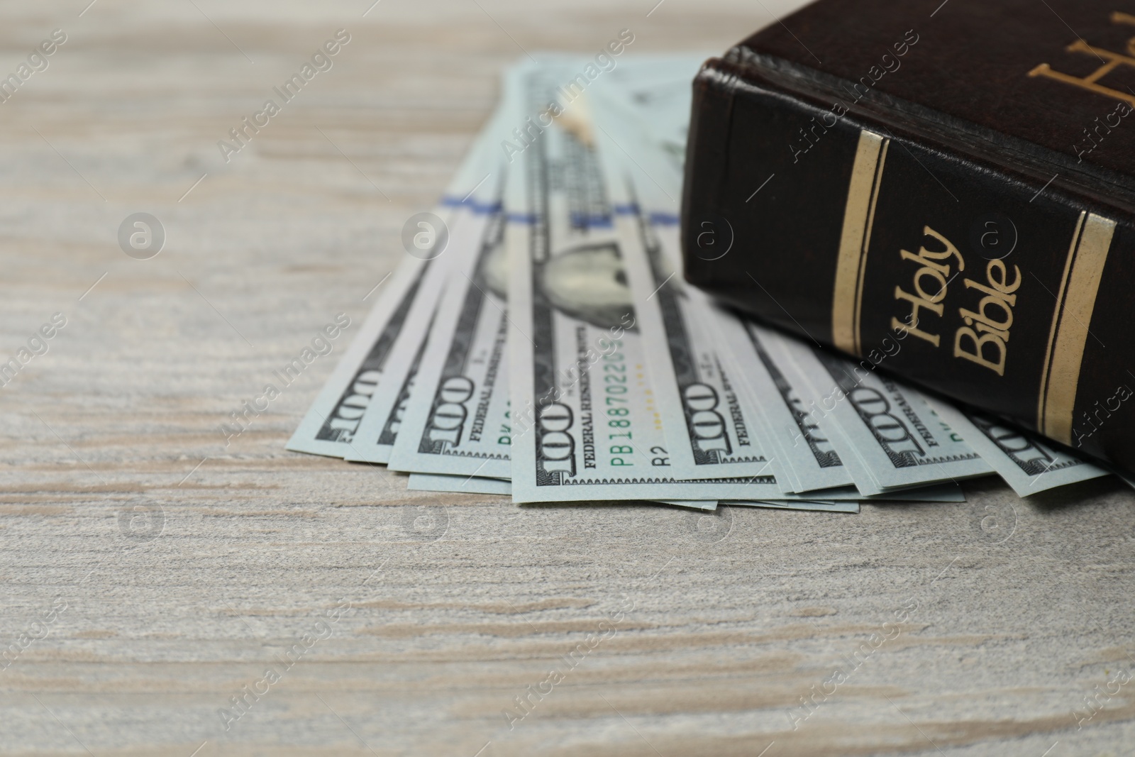 Photo of Holy Bible and money on wooden table, closeup. Space for text