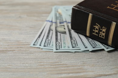 Photo of Holy Bible and money on wooden table, closeup. Space for text