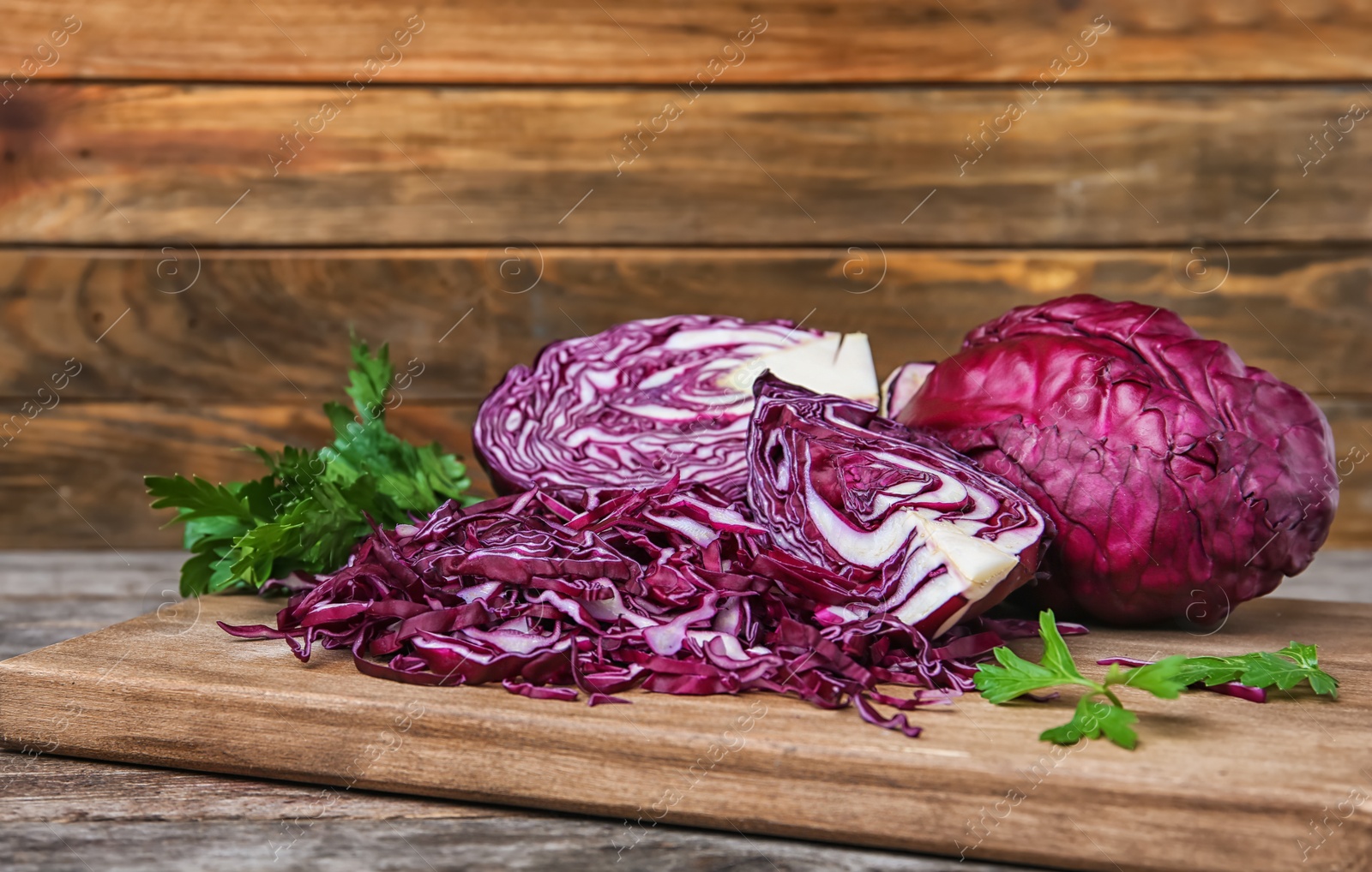 Photo of Wooden board with chopped purple cabbage and parsley on table