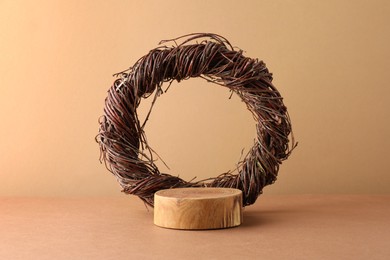 Photo of Presentation for product. Wooden podium and willow twig wreath on beige background