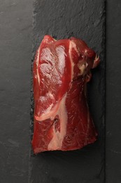 Photo of Piece of raw beef meat on black table, top view