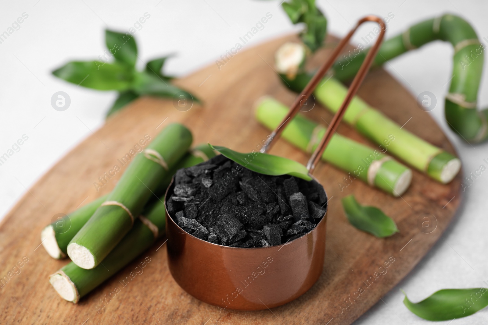 Photo of Fresh bamboo and charcoal on wooden board, closeup