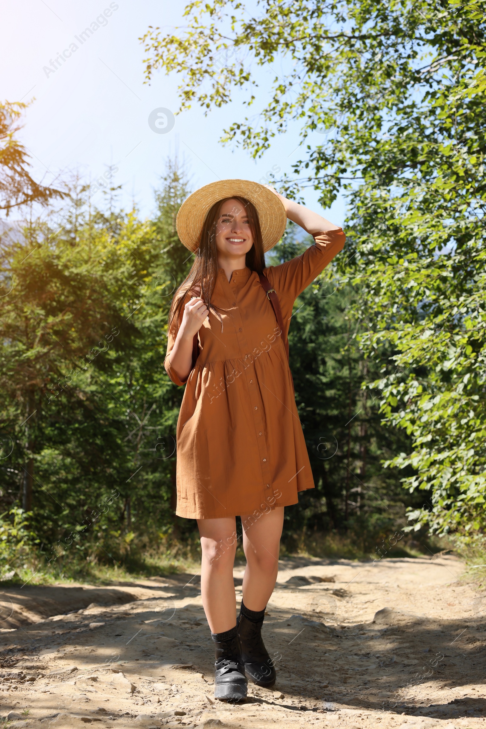 Photo of Happy woman with backpack and hat enjoying her walk in forest