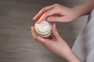 Woman applying hand cream indoors, above view