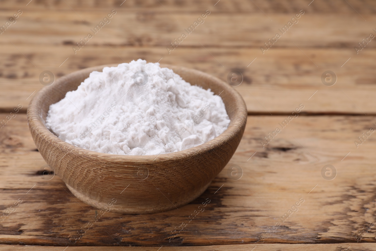 Photo of Bowl of natural starch on wooden table, closeup. Space for text