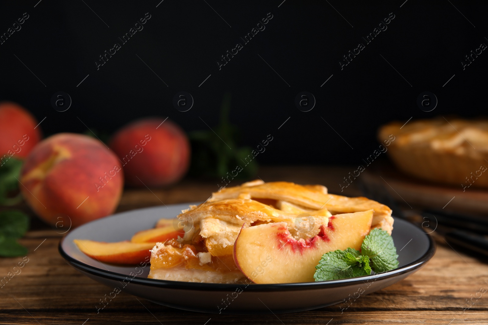 Photo of Piece of delicious fresh peach pie served on wooden table, closeup