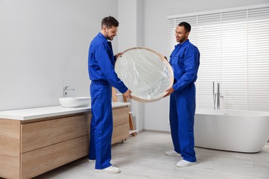 Photo of Male movers with mirror in bathroom. New house