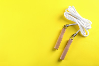 Photo of Skipping rope on yellow background, top view. Space for text