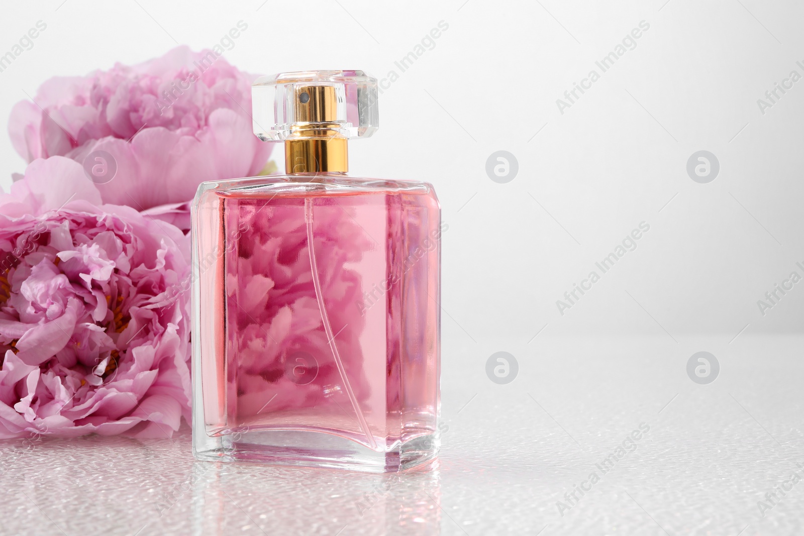 Photo of Luxury perfume and floral decor on plastic surface, space for text