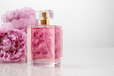 Luxury perfume and floral decor on plastic surface, space for text