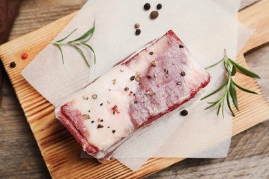 Photo of Tasty salt pork with rosemary and spices on wooden table, top view