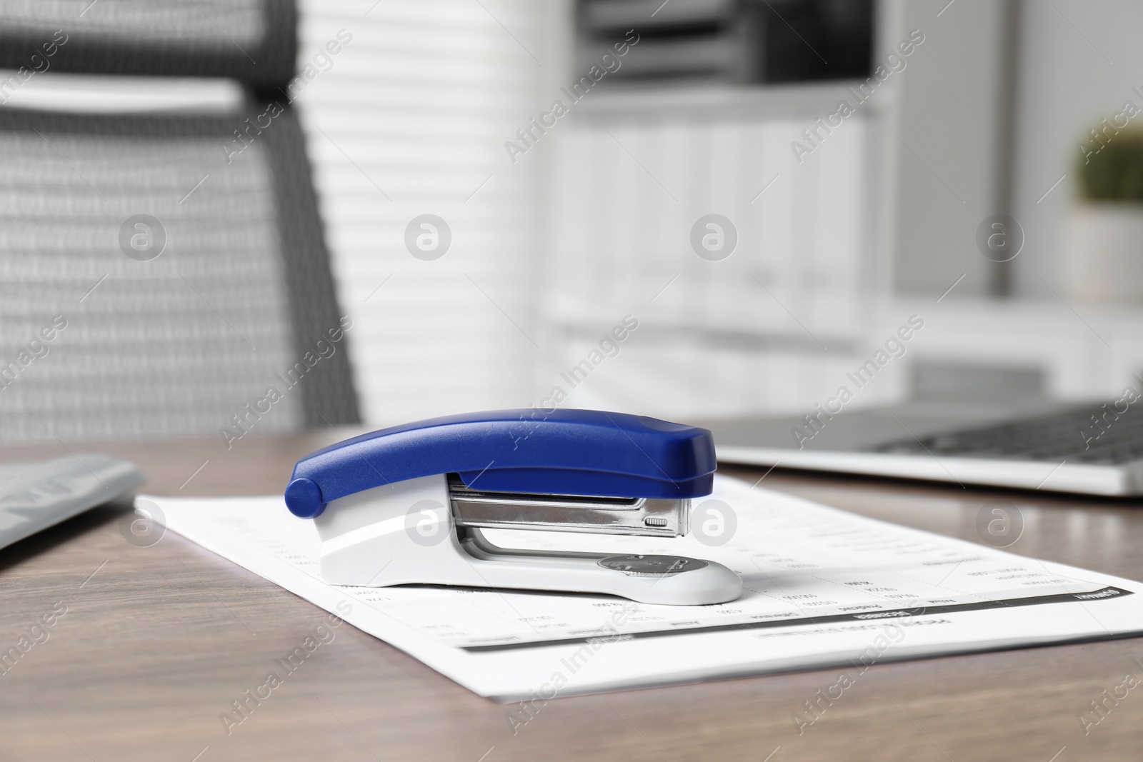 Photo of Bright stapler and document on wooden table indoors