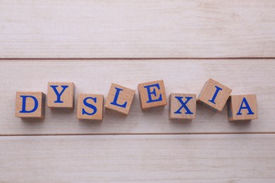 Photo of Cubes with word Dyslexia on wooden table, flat lay