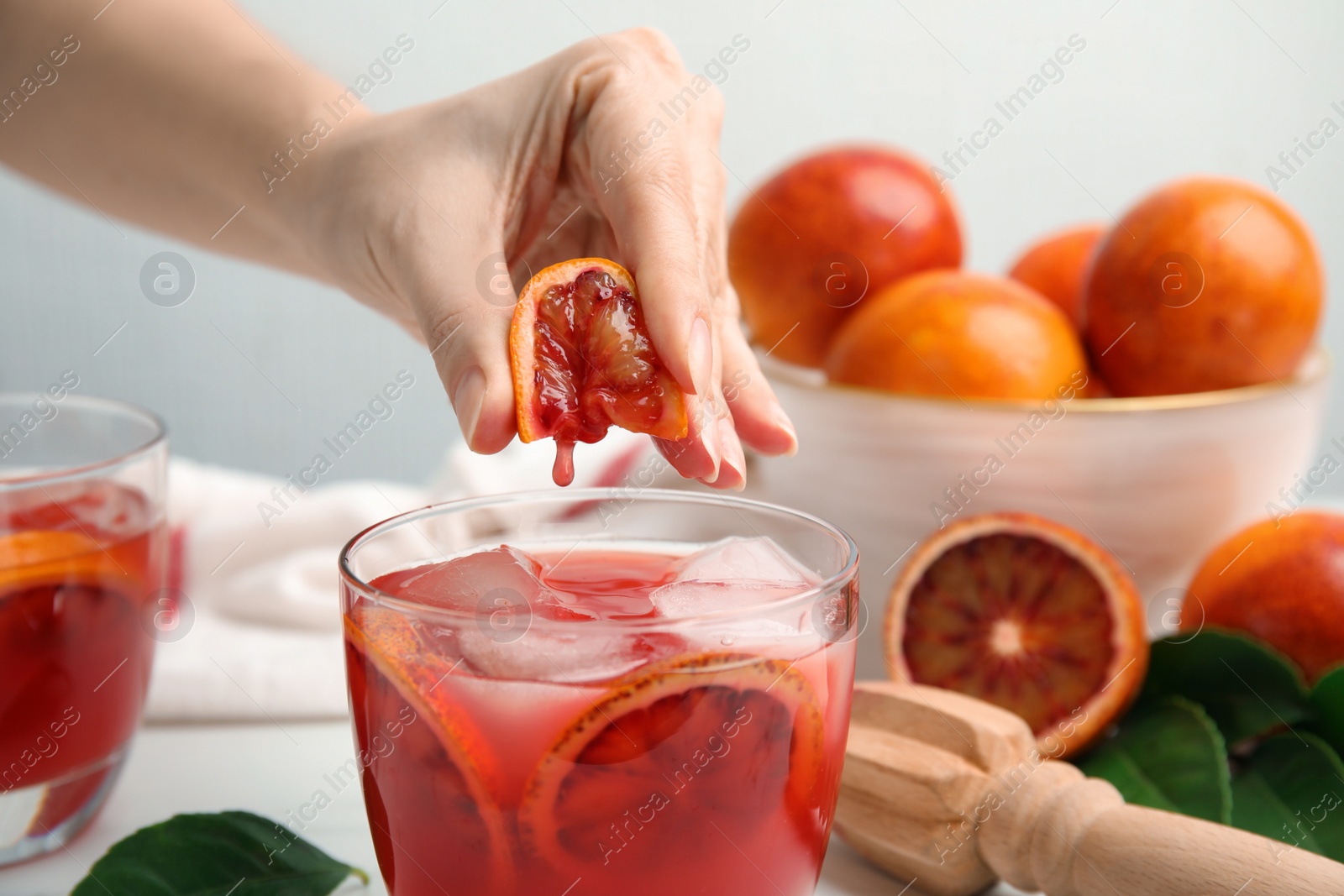 Photo of Woman squeezing sicilian orange juice into glass, closeup