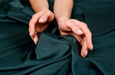Photo of Woman touching soft dark green fabric, closeup
