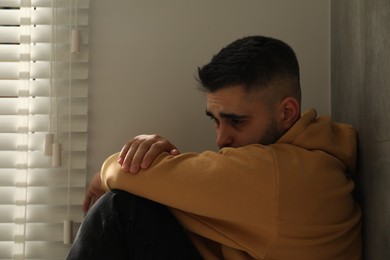 Photo of Sad man sitting near window at home