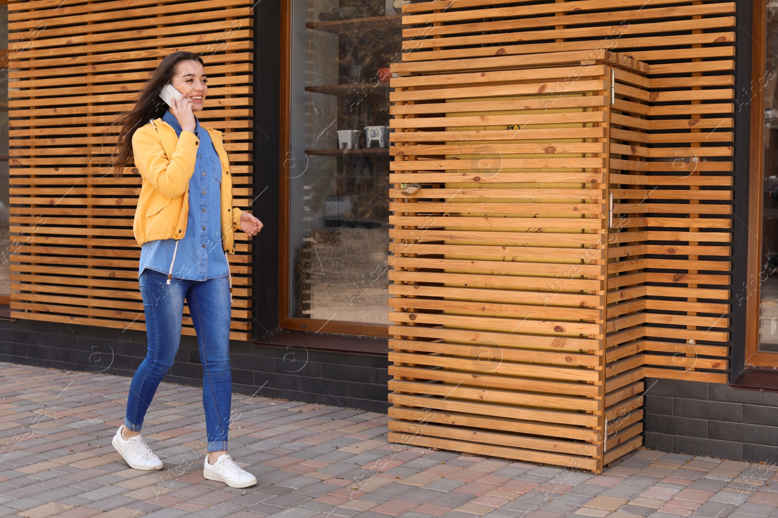 Photo of Beautiful young woman talking on phone outdoors