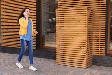 Photo of Beautiful young woman talking on phone outdoors