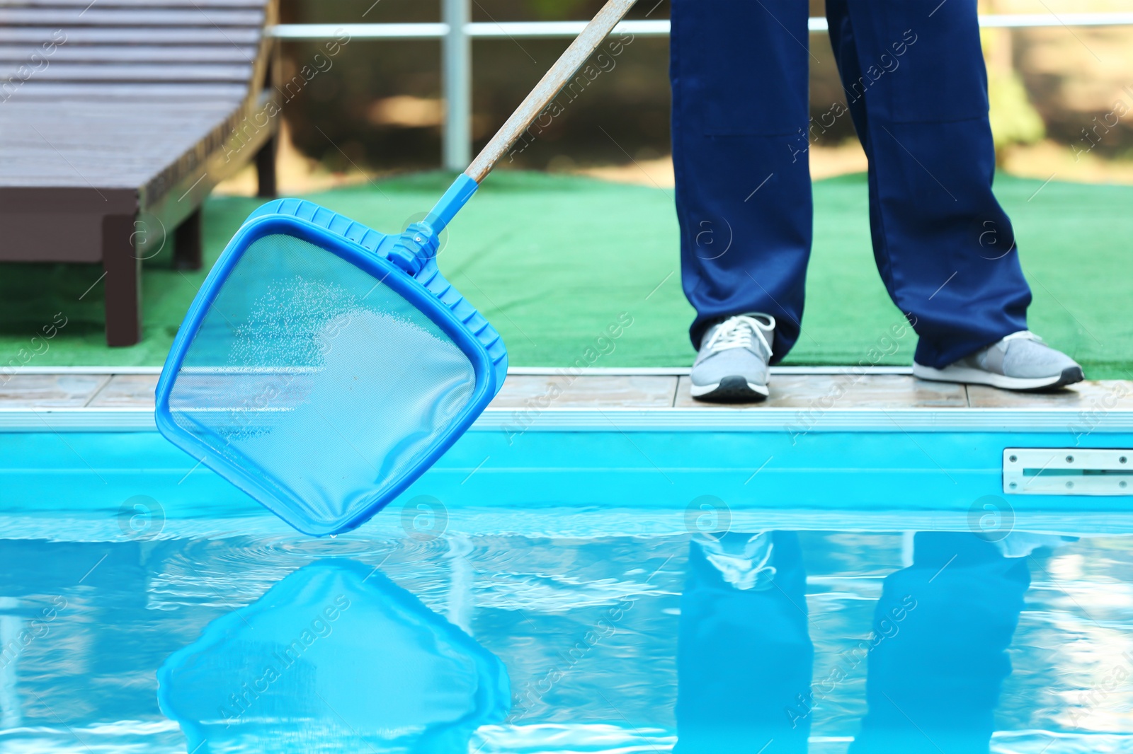 Photo of Male worker cleaning outdoor pool with scoop net