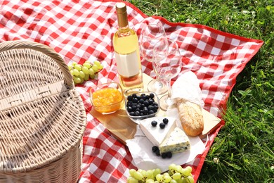 Photo of Picnic blanket with delicious food and wine outdoors on summer day