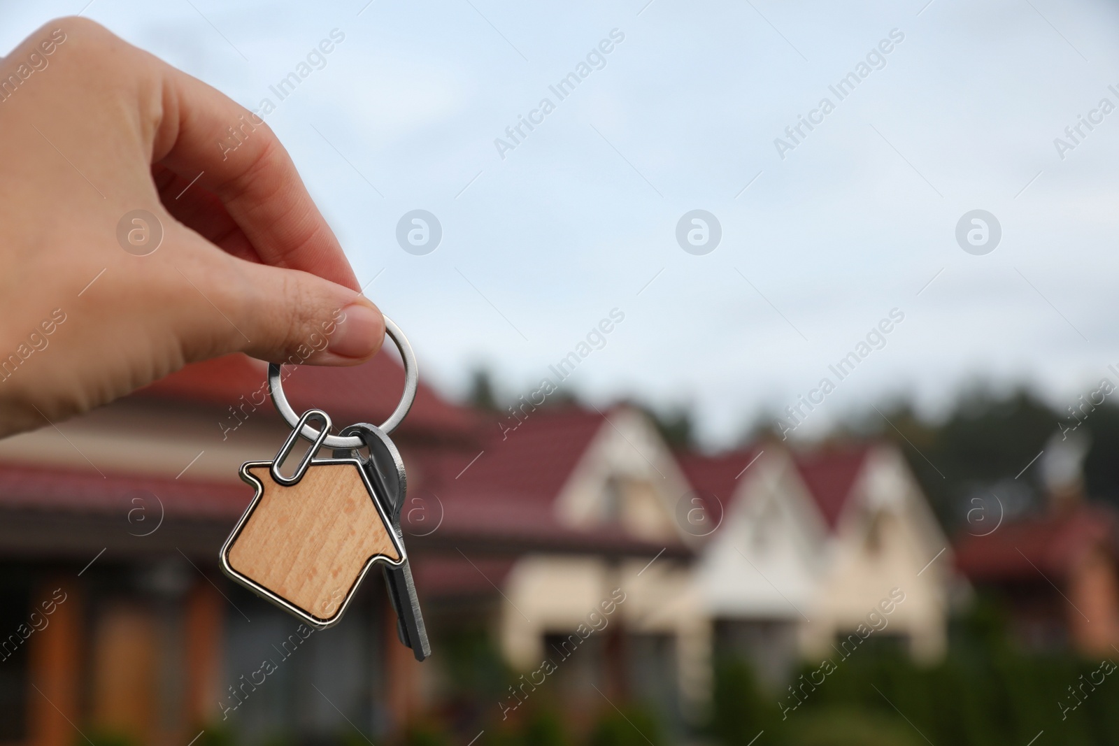 Photo of Woman holding house keys outdoors, closeup with space for text. Real estate agent