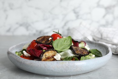 Photo of Delicious salad with roasted eggplant, basil and cheese served on grey marble table