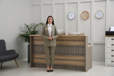 Photo of Full length portrait of beautiful receptionist near counter in hotel