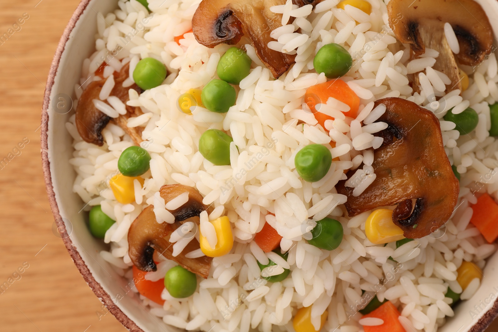 Photo of Bowl of delicious rice with vegetables on table, top view