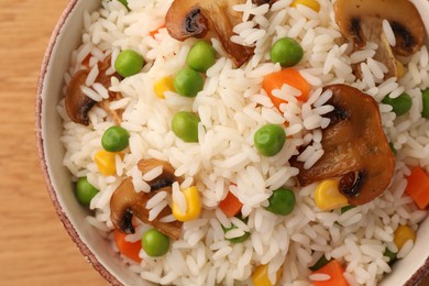 Bowl of delicious rice with vegetables on table, top view