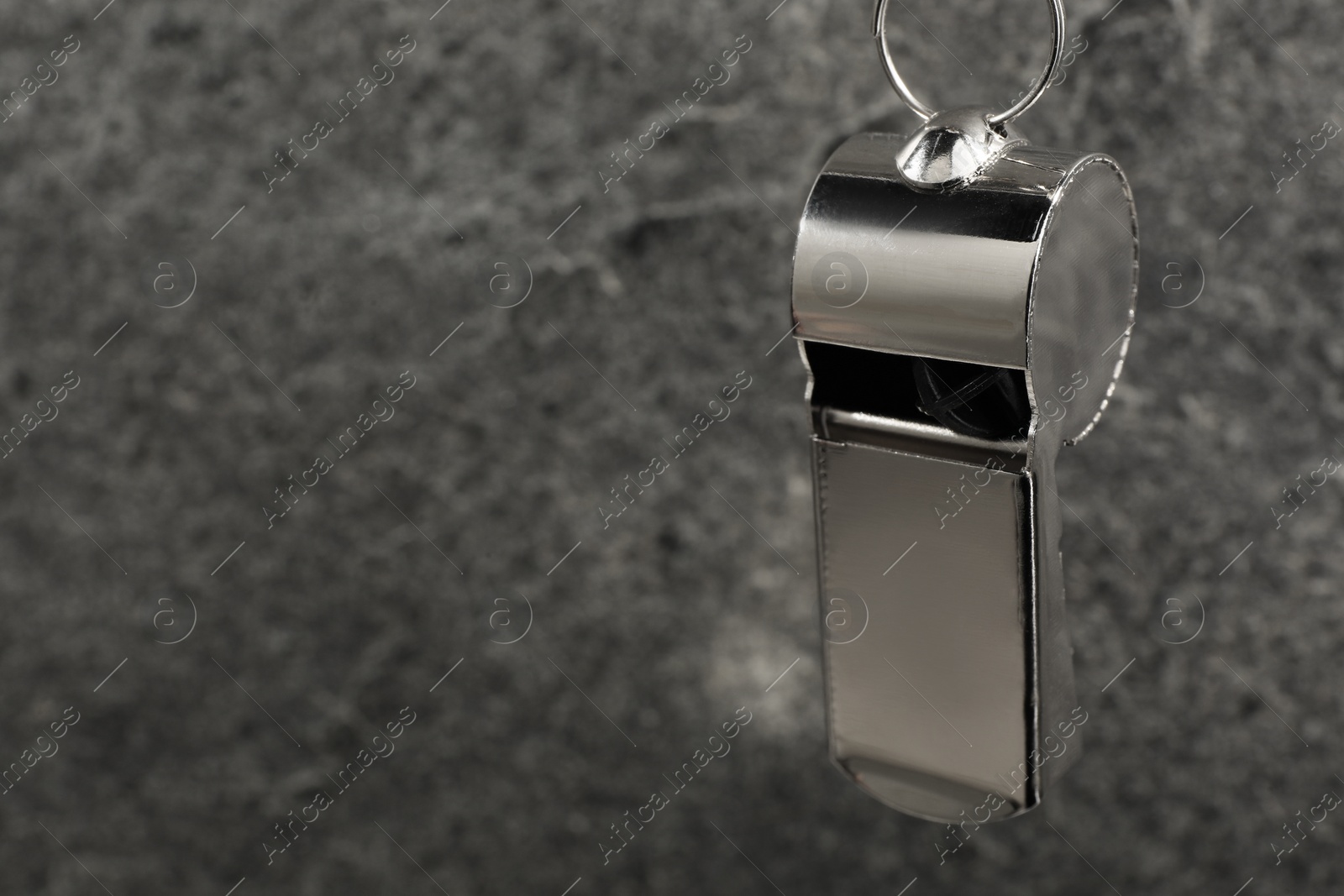 Photo of Referee equipment. Metal whistle on grey textured background, closeup and space for text